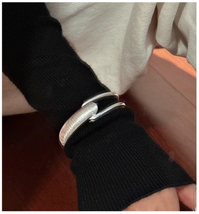 Detail of S925 sterling silver cuff with brushed texture worn over black knit sleeve