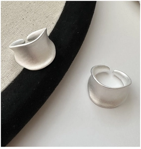 Macro-opname van twee matte S925 zilveren open ringen op een beige canvas ondergrond