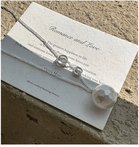 Macro shot of silver ball pendant featuring hammered texture and dual ring accents
