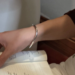 Minimalist S925 sterling silver wavy bangle with a polished finish worn on a wrist