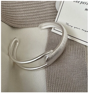 Macro shot of minimalist S925 silver cuff bracelet featuring a brushed texture finish