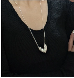 Close-up of polished S925 sterling silver heart pendant necklace on a black sweater