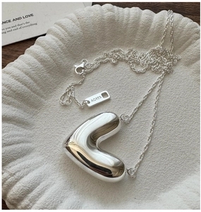 Macro detail of S925 sterling silver heart necklace with 3D polished finish and AG925 tag