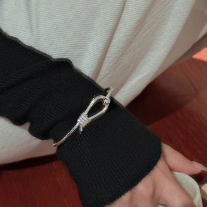 Minimalist S925 sterling silver hollow knot cuff bracelet worn over black knit sleeve