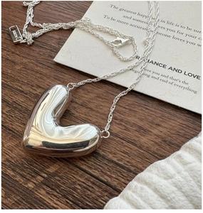 Macro shot of 3D hollow heart pendant in AG925 silver on rustic wood background