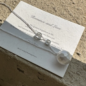 Artistic shot of a S925 sterling silver hammered ball necklace on textured paper
