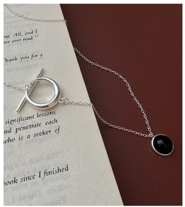 Detail of silver OT buckle and round black onyx pendant on vintage book pages