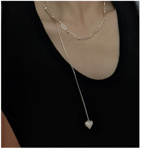 Detail of S925 sterling silver layered necklace with heart pendant on black knitwear