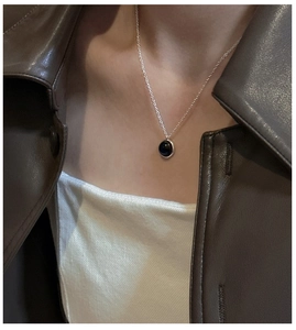 Detail view of S925 sterling silver necklace with round black agate pendant on model