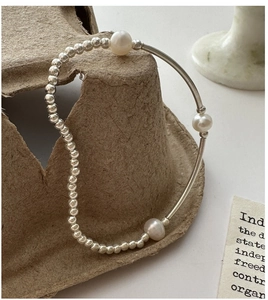 Detail of S925 silver bracelet featuring natural pearls and smooth metal tube on display