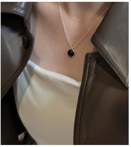 Macro shot of minimalist S925 sterling silver necklace with a round black onyx pendant