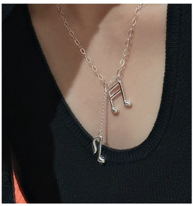 Détail du collier pendentif note de musique en argent avec chaînes à glands sur un mannequin