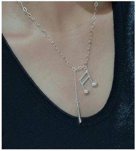 Détail d'un collier en argent S925 avec pendentif note de musique et pompon sur un mannequin