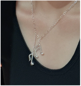 Gros plan sur le collier en argent avec pendentif note de musique et finition polie