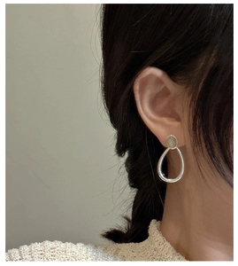 Detail view of water drop silver earrings with grey moonstone on model's ear