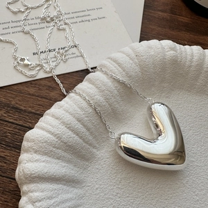 Polished S925 sterling silver hollow heart pendant necklace with rope chain on ceramic tray