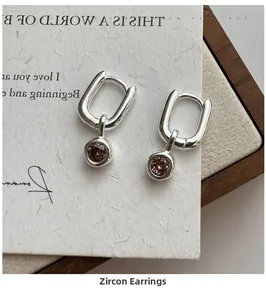 Macro detail of S925 silver hoop earrings with a sparkling brown zircon pendant drop