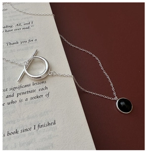 Detailed view of S925 silver OT buckle necklace with black agate pendant on vintage book