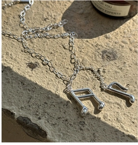 Gros plan des pendentifs notes de musique en argent S925 sur une surface en pierre