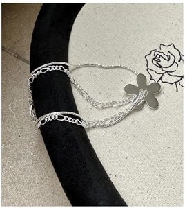 Détail du bracelet double rang argenté avec chaîne Figaro et pendentif de fleur