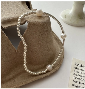 Close-up of S925 silver beaded bracelet with three elegant white pearls on a minimalist base