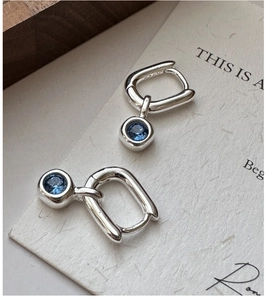 Close-up of S925 sterling silver hoop earrings with a dangling round blue zircon stone