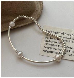Detailed shot of S925 silver beaded bracelet featuring three natural pearls on felt background