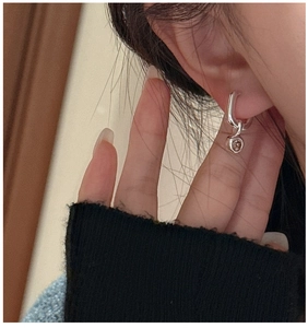 Macro shot of S925 sterling silver earring with a round brown zircon pendant on the ear