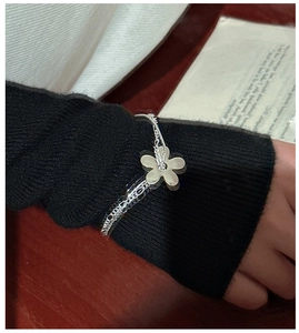 Gros plan du bracelet en argent à plusieurs couches avec pendentif fleur sur manche noire