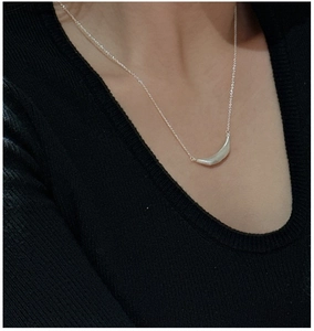 Close-up of S925 sterling silver smile necklace with matte finish on black fabric