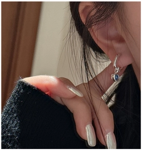 Detail of S925 silver earring with blue sphere pendant on model in natural lighting