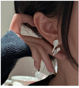 Close-up of minimalist silver leaf stud earrings with a matte texture on a model's ear