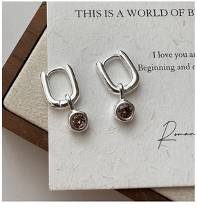 Macro shot of S925 silver U-shaped hoop earrings with sparkling champagne zircon pendant