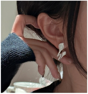 Macro shot of S925 sterling silver leaf earrings with a matte organic finish on ear