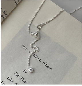 Detailed close-up of a silver Chopin necklace with a single zircon on an open book