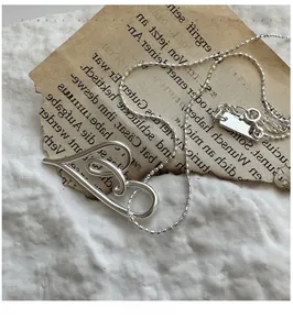 Detail of S925 silver heart necklace with ball chain on vintage paper background