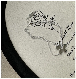 Gros plan d'un bracelet double épaisseur en argent avec pendentif fleur et maille Figaro