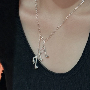 Élégant collier en argent S925 avec pendentif note de musique porté sur un tricot noir