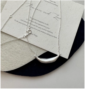Detail of S925 sterling silver smile necklace with brushed matte finish on a poetic card