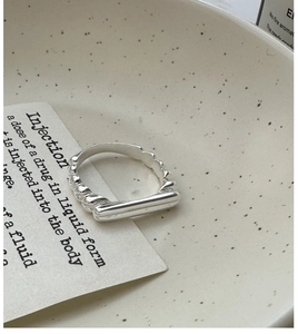 Detailed view of S925 silver ring featuring a twisted band and smooth bar on a ceramic plate