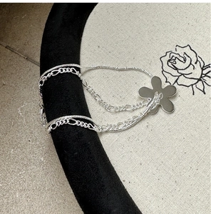Détail d'un bracelet double couche en argent S925 avec un pendentif fleur minimaliste