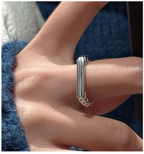 Detail of S925 silver minimalist rectangular ring with textured band worn on finger
