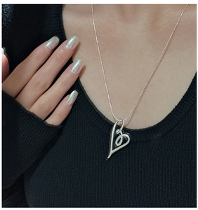 Close-up of a hollow curved heart pendant necklace in silver worn on neck by a model