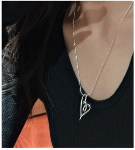 Macro shot of silver open heart knot pendant necklace on elegant dark knitwear