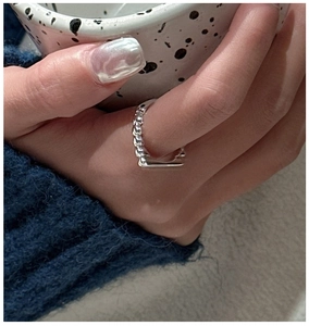 Detail of S925 sterling silver twisted rope ring worn by a model in a cozy setting