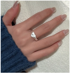 Detail view of a matte S925 sterling silver heart ring worn on a finger with knit sleeve