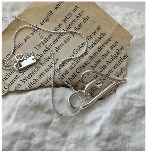 Macro shot of S925 sterling silver hollow heart pendant on vintage German paper