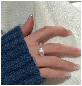 Macro detail of S925 sterling silver ring with brushed almond charm on model's hand