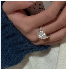 Macro detail of S925 sterling silver ring with abstract floral design on model finger