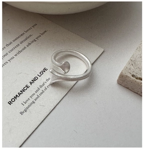 Macro shot of minimalist silver wrap ring with a matte finish and artistic fluid design